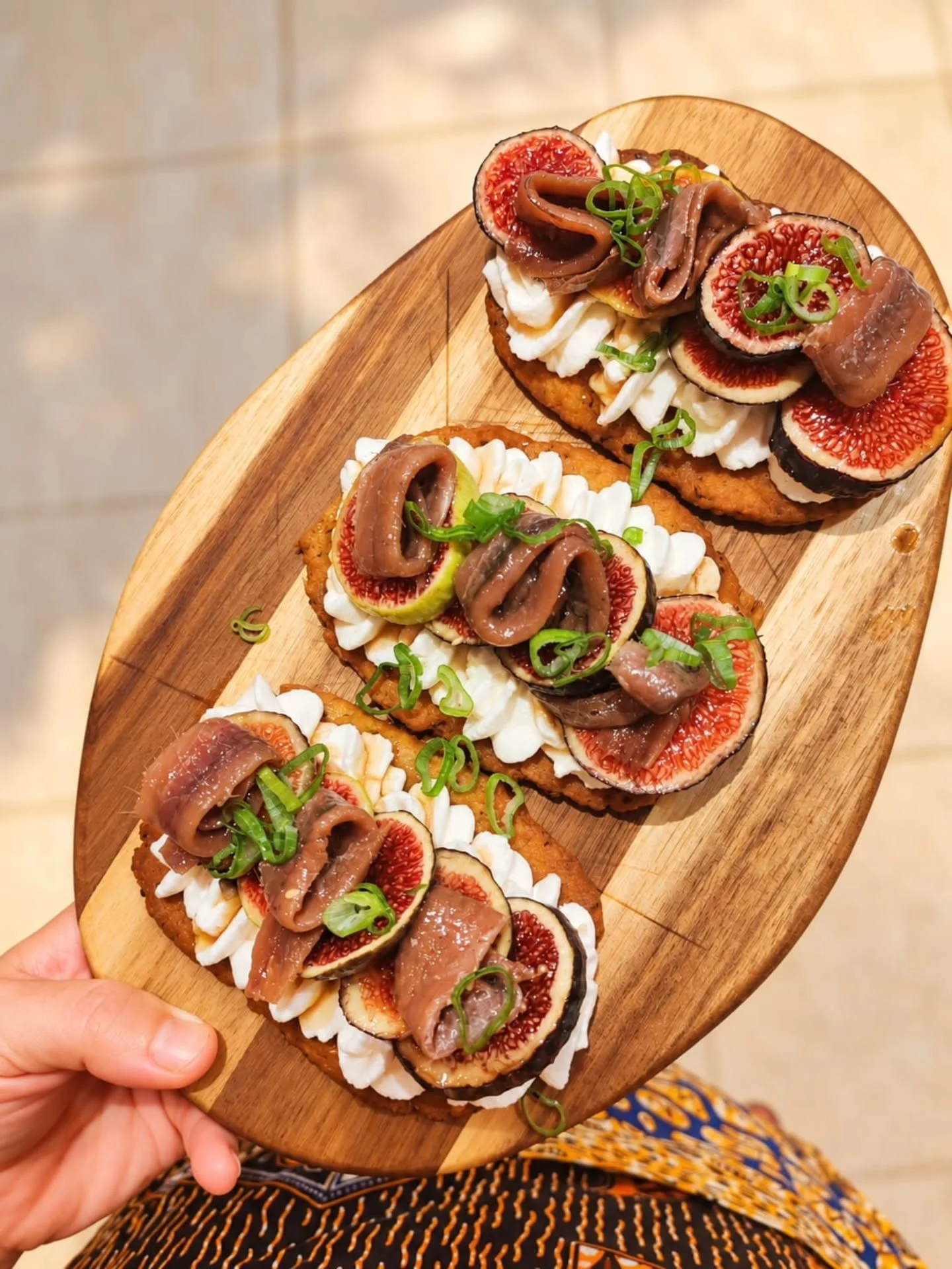 Tres cruixents amb ricotta, figues i anxoves damunt una post de fusta